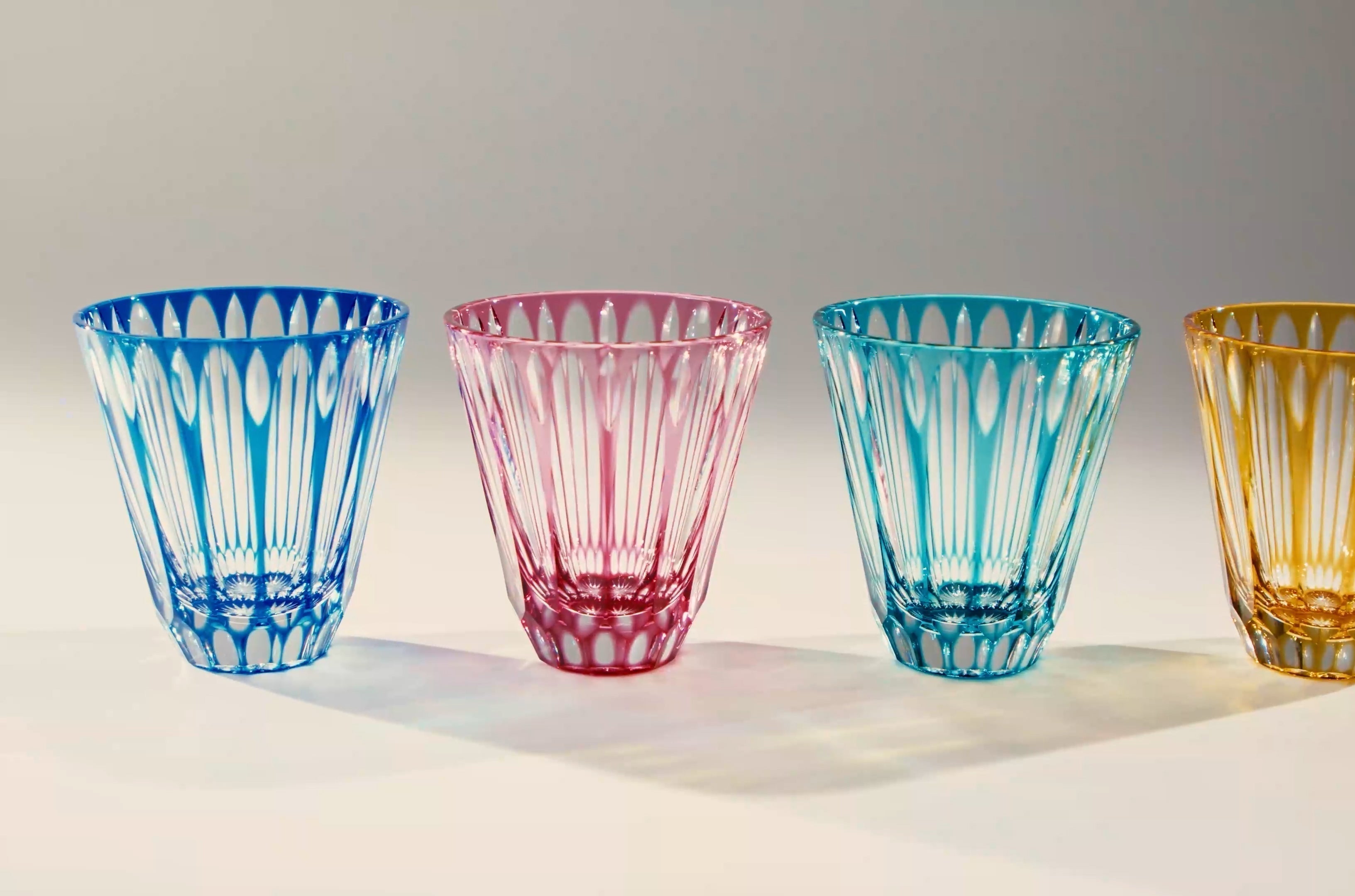 Four Temma Kiriko cut glasses in different colors: blue, pink, blue-green, and amber.